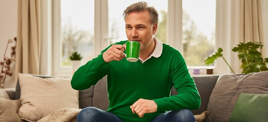 Mann trinkt Tee, um Hausmittel gegen seine Erkältung auszuprobieren.
