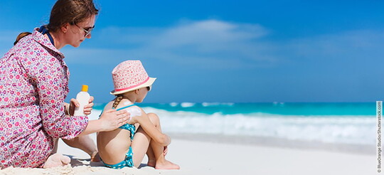 Reiseapotheke: Sonnenschutz. Mutter cremt Kind ein