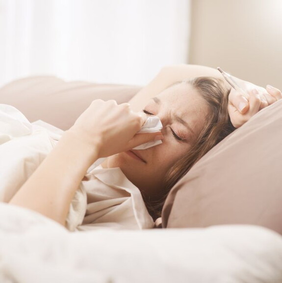 Frau leidet im Verlauf einer Erkältung an Fieber und Gliederschmerzen