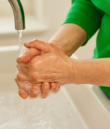 Mann wäscht sich gründlich die Hände unter einem Wasserhahn
